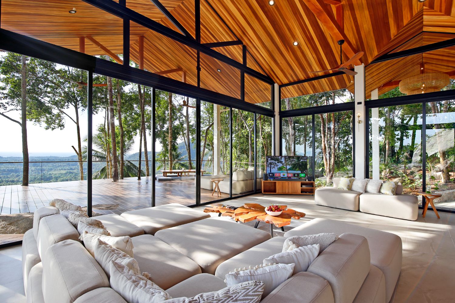 Living room at Villa Ullassa with pale linen sofas under a high raked teak ceiling and glass walls open to the jungle
