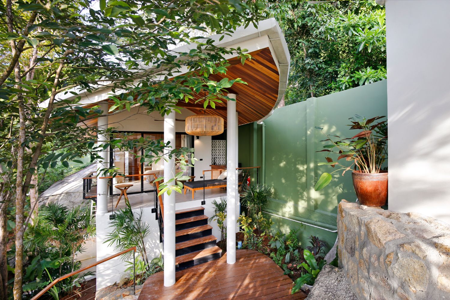 The entrance to one of the buildings: timber steps up to a covered porch, green wall and potted plants