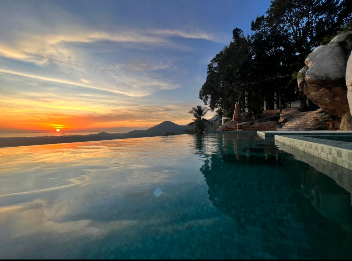 The villa's infinity pool at sunset, its surface level with the horizon above the sea